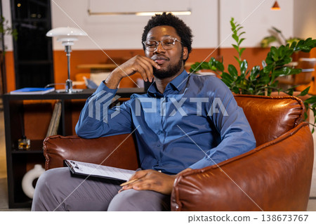 Man in glasses sitting in armchair thinking Man in glasses sitting in armchair thinking 138673767