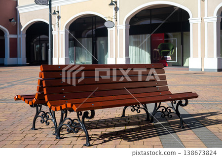 Bench placed in an open area near shops during daytime with clear sky 138673824