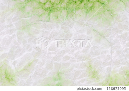 A background of Tosa handmade washi paper with a white background showing green color variations. A background of Tosa handmade washi paper with a white background showing green color variations. 138673995