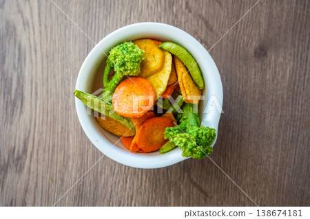 Mixed vegetable chips in bowl with broccoli, carrot, peas and sweet potato on wooden table. Healthy snack and clean eating concept without salt sugar or additives. Mixed vegetable chips in bowl with broccoli, carrot, peas and sweet potato on wooden table. Healthy snack and clean eating concept without salt sugar or additives. 138674181