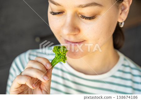 Woman eating broccoli chip as healthy snack at home. Mindful eating and clean diet concept with natural vegetable food. 138674186