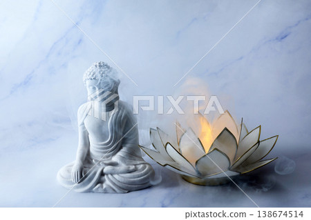Vesak Buddha birthday. Buddha statue meditating near glowing lotus candle with smoke Vesak Buddha birthday. Buddha statue meditating near glowing lotus candle with smoke 138674514