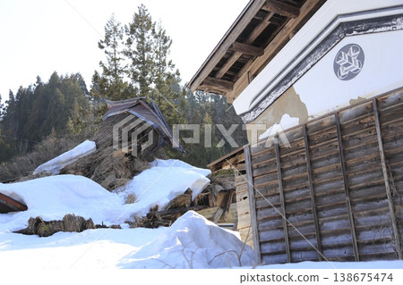 A clear, sunny day in the Oginoshima circular thatched-roof village, with snow still remaining. Thatched-roof houses and storehouses bearing family crests, decayed under the weight of the snow. 138675474