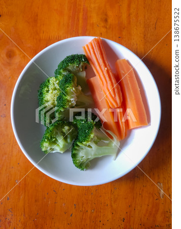 Steamed Broccoli and Sliced Carrots on a White Plate 138675522