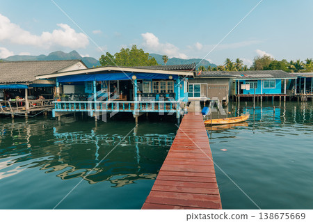 Wooden pier leading to a colorful blue stilt house in a coastal fishing village Wooden pier leading to a colorful blue stilt house in a coastal fishing village 138675669