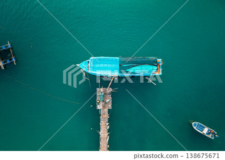 Top down aerial view of a traditional blue wooden boat moored at a pier in turquoise water Top down aerial view of a traditional blue wooden boat moored at a pier in turquoise water 138675671