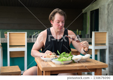 Caucasian Man Eating Grilled Liver Skewer with Thai Isan Food Som Tum Papaya Salad Outdoor Table Caucasian Man Eating Grilled Liver Skewer with Thai Isan Food Som Tum Papaya Salad Outdoor Table 138676090