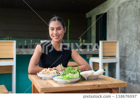 Smiling Young Thai Woman Dining with Traditional Isan Food Som Tum Papaya Salad on Wooden Table 138676097