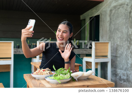 Happy Thai Woman Video Calling with Smartphone at Restaurant Table with Isan Food Papaya Salad Happy Thai Woman Video Calling with Smartphone at Restaurant Table with Isan Food Papaya Salad 138676100
