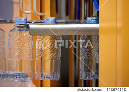 Close-up of finished PET bottles moving on a conveyor belt after the blow molding process in a modern facility. 138676138