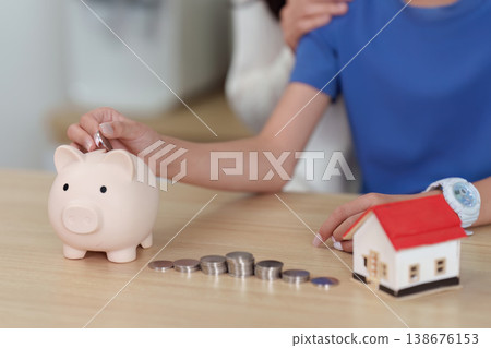 Child saving money with piggy bank and toy house 138676153