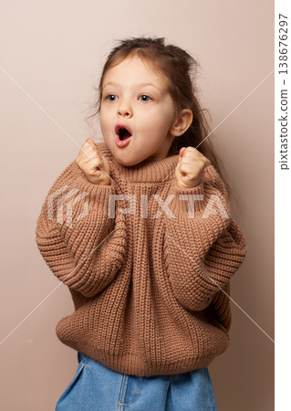 little child girl experiencing surprise with wide eyes and open mouth in a cozy sweater 138676297