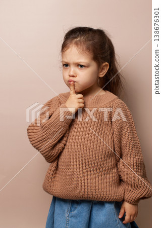 Young child girl covering mouth signaling silence or secret on beige background Young child girl covering mouth signaling silence or secret on beige background 138676301