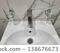 The bathroom has a white handwashing sink with glass accessories 138676673