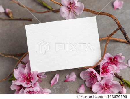 Blank card mockup with pink cherry blossoms and twigs on grey stone. Spring wedding stationery 138676796