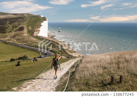 Hiker walking on a path towards the white cliffs and ocean Hiker walking on a path towards the white cliffs and ocean 138677243