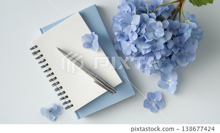 一張白色書桌上放著打開的筆記本和鋼筆，還有繡球花。 138677424