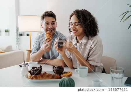 Joyful Pastry Sharing. Two People Delighting In Baked Goods With Cheerful Expressions In Warm Kitchen Setting 138677621