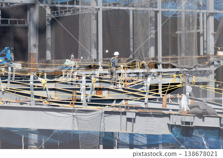 A worker marking component numbers and grid lines on columns at a steel frame construction site (Image 1) 138678021