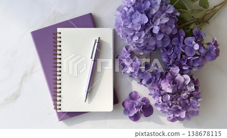 一張白色書桌上放著打開的筆記本和鋼筆，還有繡球花。 138678115