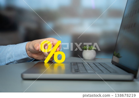 Man hand holding a percentage sign on a laptop keyboard. Man hand holding a percentage sign on a laptop keyboard. 138678219