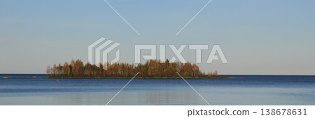 Golden forest on a small island on a autumn day at the shore of Lake Vanern, Sweden. Golden forest on a small island on a autumn day at the shore of Lake Vanern, Sweden. 138678631
