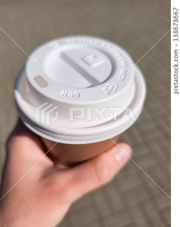 Hand holding disposable coffee cup with lid in prague Hand holding disposable coffee cup with lid in prague 138678667