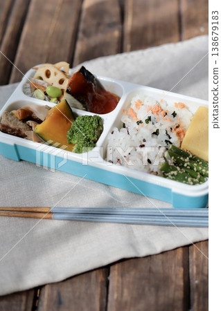A healthy Japanese bento box using a lunch box with an integrated divider. 138679183