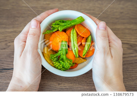 Hands holding bowl with vegetable chips made from broccoli carrot and sweet potato. Healthy snack and clean eating lifestyle concept. 138679573