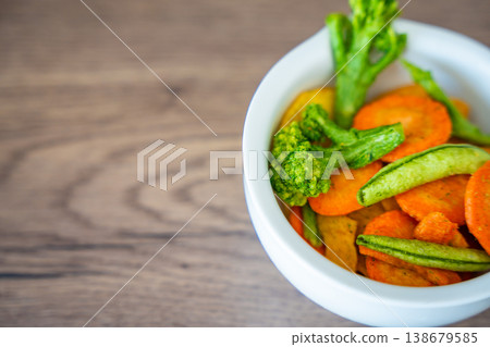 Mixed vegetable chips in bowl with copy space on wooden background. Healthy snack and clean eating concept without salt sugar or additives. Soft focus photo 138679585