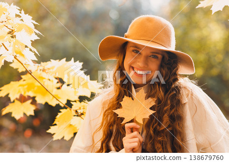 Smiling young woman portrait in the autumn forest with the yellow leaves at sunset 138679760