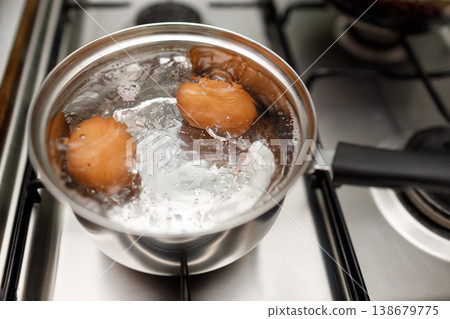 Saucepan stainless steel with boiling eggs breakfast in water on gas stove. Saucepan stainless steel with boiling eggs breakfast in water on gas stove. 138679775
