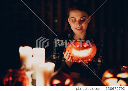 Young woman making Halloween pumpkin Jack-o-lantern with candles in dark Young woman making Halloween pumpkin Jack-o-lantern with candles in dark 138679792