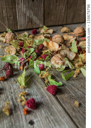 Dried delicious delicacies. Dry pieces of linden, rose hips, pears, raspberries, apples and walnuts snack on a wooden background Dried delicious delicacies. Dry pieces of linden, rose hips, pears, raspberries, apples and walnuts snack on a wooden background 138679796