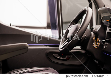 Interior view of a modern vehicle cabin featuring a black steering wheel and minimalist dashboard design. Interior view of a modern vehicle cabin featuring a black steering wheel and minimalist dashboard design. 138680406