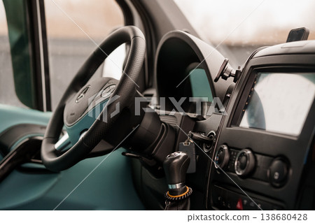 Close up view of a dark dashboard and steering wheel inside a commercial transport vehicle interior 138680428