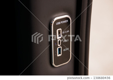 Close-up of vehicle USB power panel featuring three charging ports for mobile devices embedded in black leather interior trim Close-up of vehicle USB power panel featuring three charging ports for mobile devices embedded in black leather interior trim 138680436