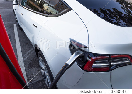 White electric car plugged into a public charging station 138681481
