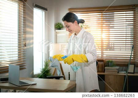 Woman cleaning home office desk with disinfectant spray 138682263