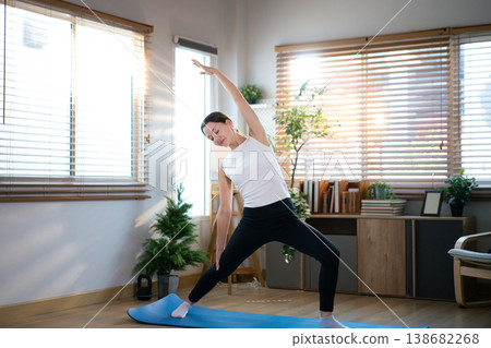 Female athlete performing extended side stretch during indoor yoga session Female athlete performing extended side stretch during indoor yoga session 138682268