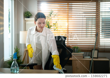 Woman cleaning home office desk with disinfectant spray 138682271