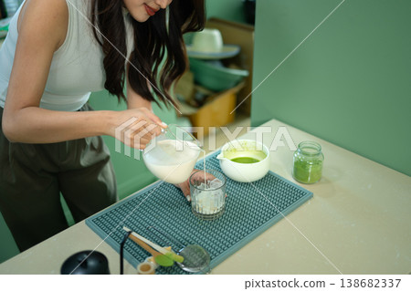 Closeup woman pouring milk over ice to make iced matcha latte 138682337