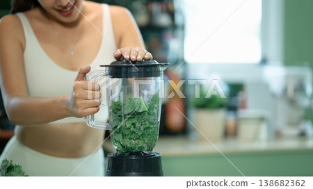 Close up of woman holding blender with fresh kale inside Close up of woman holding blender with fresh kale inside 138682362