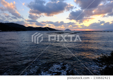 夕陽西下,一艘木筏漂浮在光線昏暗的宇和海上。 夕陽西下,一艘木筏漂浮在光線昏暗的宇和海上。 138682421