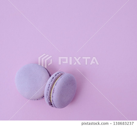 Pair of lavender French macarons on solid lilac background, purple monochrome dessert photography for cafe menu Pair of lavender French macarons on solid lilac background, purple monochrome dessert photography for cafe menu 138683237