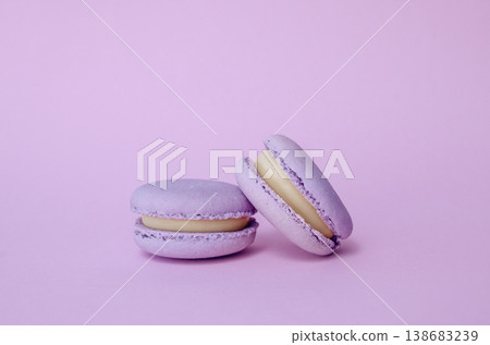 Pair of lavender French macarons on solid lilac background, purple monochrome dessert photography for cafe menu Pair of lavender French macarons on solid lilac background, purple monochrome dessert photography for cafe menu 138683239