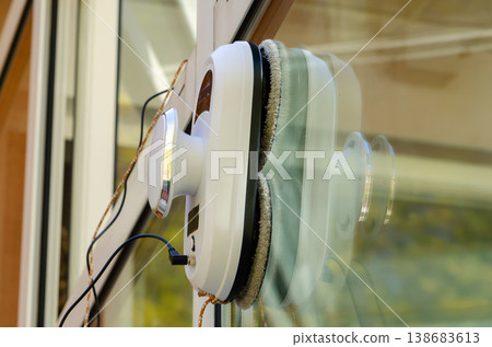 Window cleaning robot with round pads cleans glass surface leaving shine in daylight 138683613