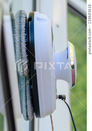 Close up of window cleaning robot attached to glass showing automatic cleaning process Close up of window cleaning robot attached to glass showing automatic cleaning process 138683616