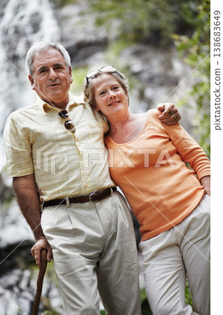 Elderly, man and woman with portrait by mountain for travel, sightseeing or holiday with happiness. Senior, couple and face with smile for cascade, vacation and adventure on retirement or tourism 138683649