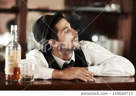 Whiskey, bar and bartender smoking and drinking in club to relax in waiting for a customer. Alcohol, drink and barman with cigarette, smoke and scotch in glass bottle on table or counter at work 138684713